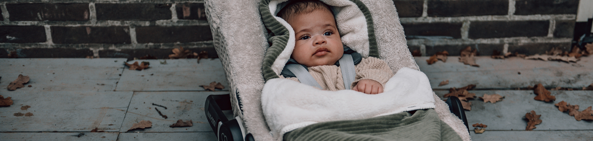 Baby zit heerlijk warm in een Koeka voetenzak in de autostoel 0+. De voetenzak is gemaakt van katoenen wafelstof, gevoerd met teddystof in de kleur moss.